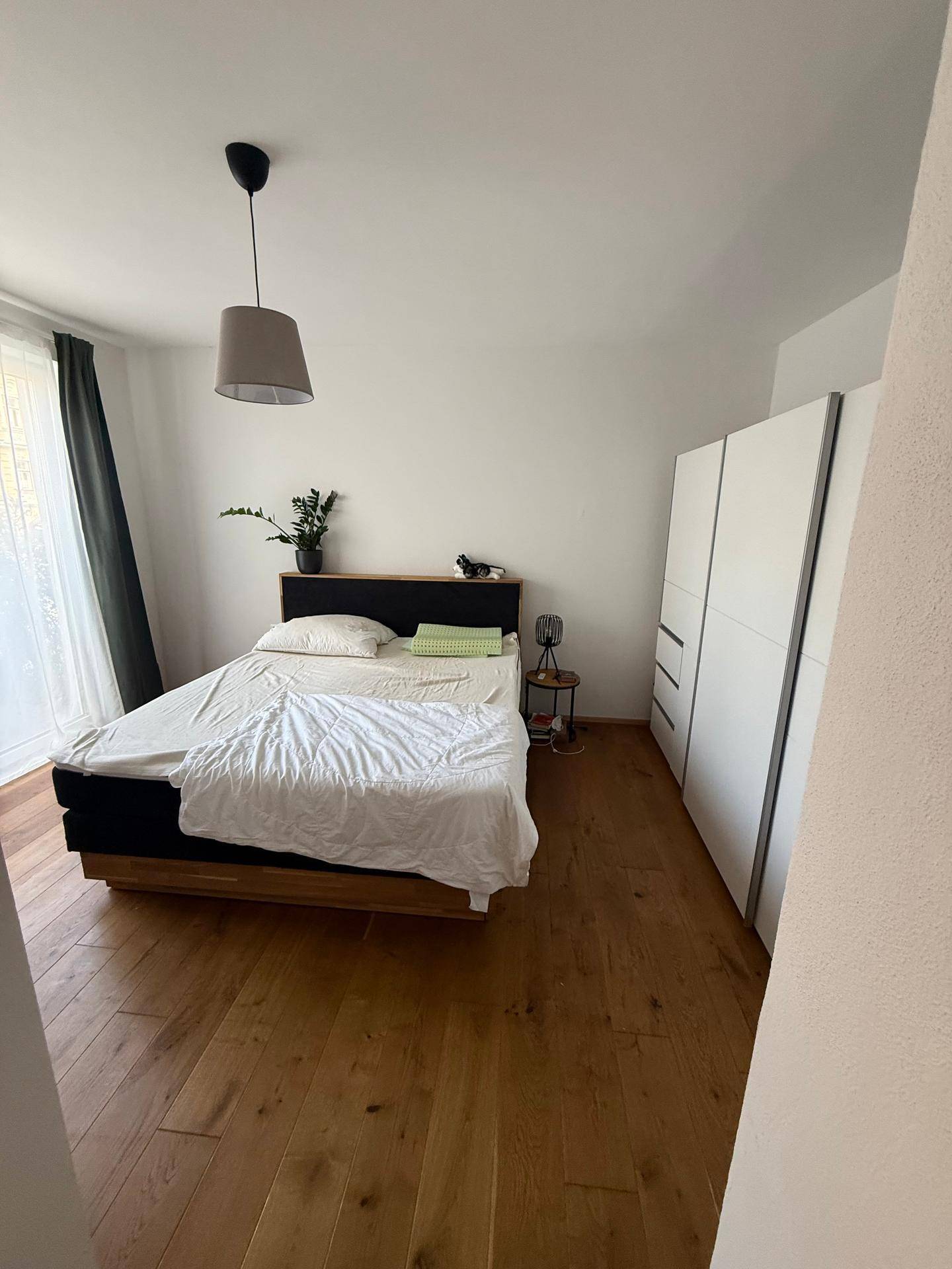 Helles Schlafzimmer mit Holzboden, einem Doppelbett und einem großen weißen Kleiderschrank.