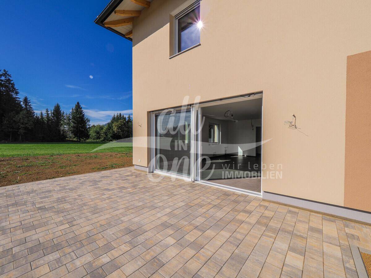 Große gepflasterte Terrasse mit direktem Zugang zum Wohnbereich durch moderne Schiebetüren.