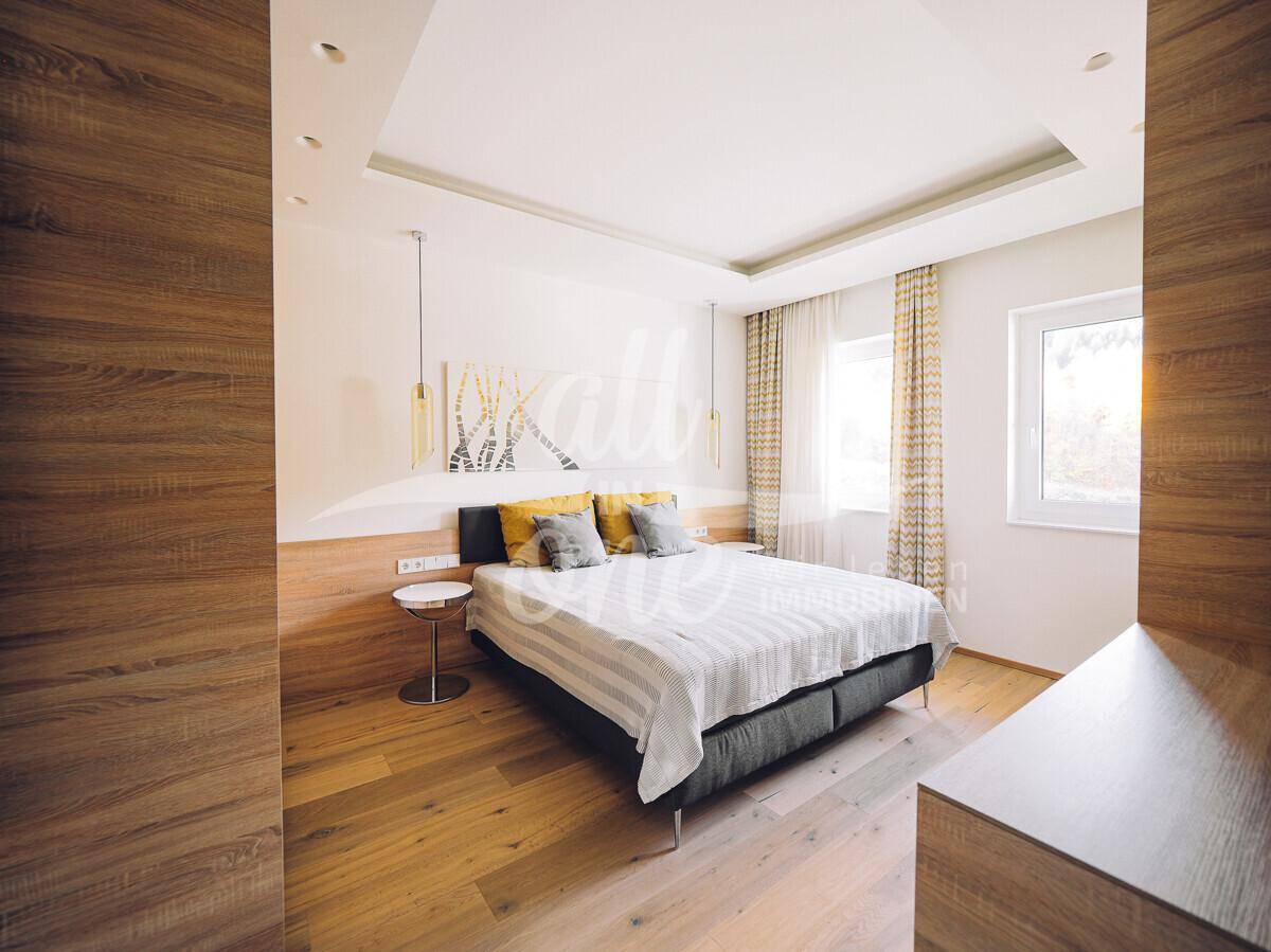 Geräumiges Schlafzimmer mit Holzboden, modernem Bett und indirekter Deckenbeleuchtung.