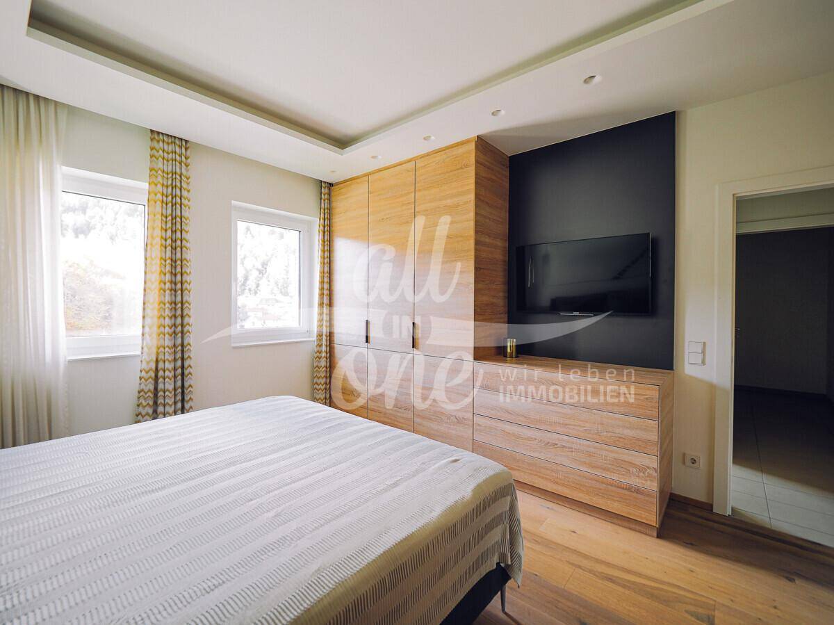 Schlafzimmer mit Einbauschränken aus Holz, integriertem Fernseher und Holzboden.
