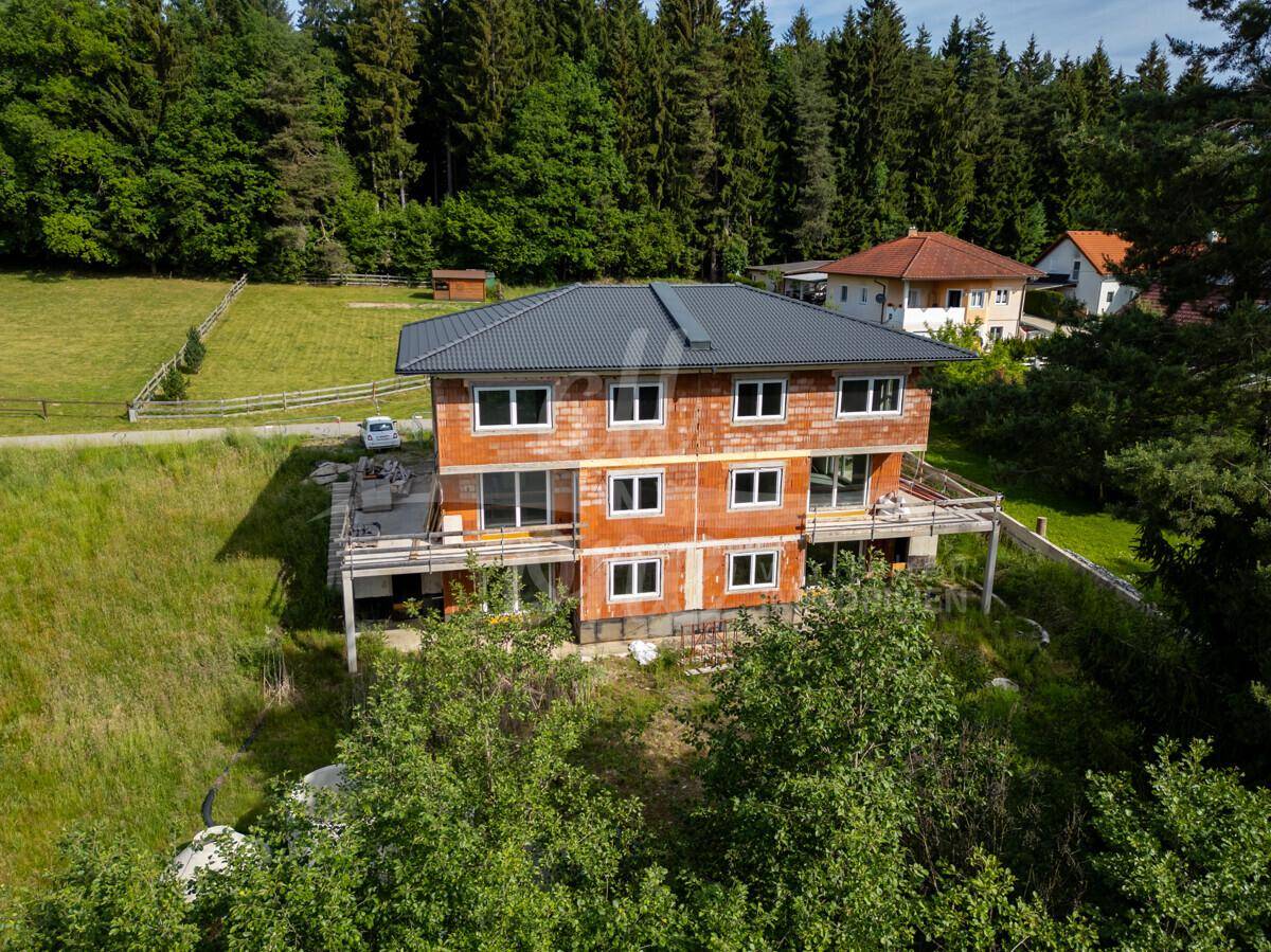 Neubau im Rohbauzustand mit Blick auf umliegende Wälder und Wiesen.