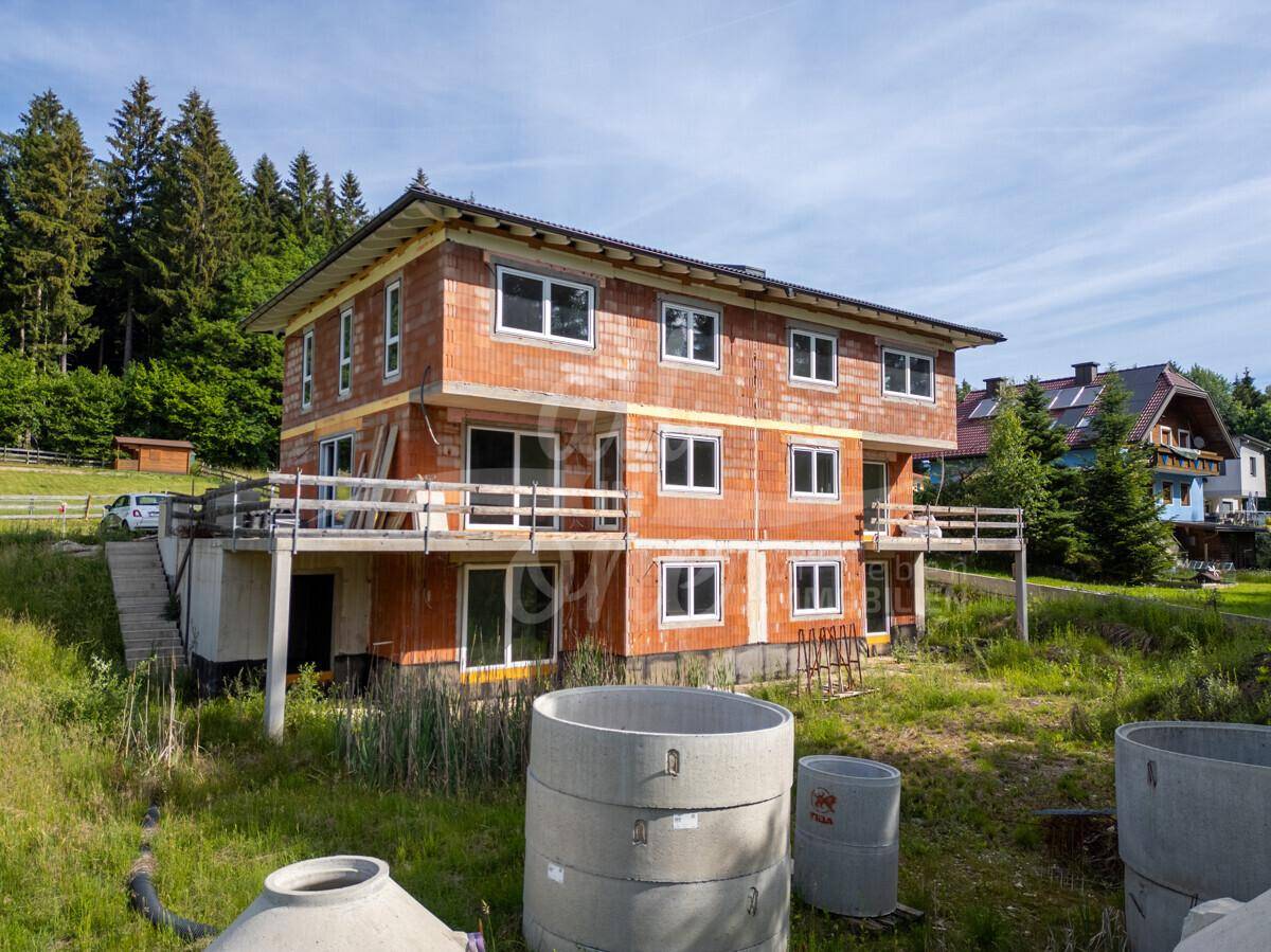 Neubau im Rohbauzustand mit sichtbaren Ziegeln und vorbereiteten Balkonbereichen.