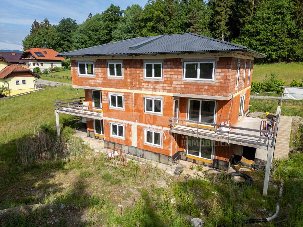 Neubau im Rohbau mit mehreren Balkonen und Blick auf die grüne Umgebung.