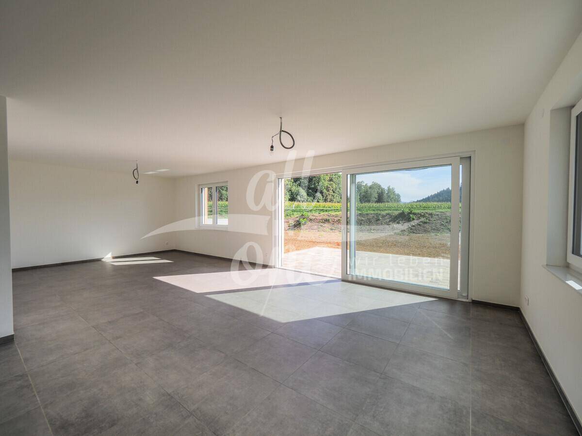 Helles Wohnzimmer mit großzügigen Schiebetüren, die viel Tageslicht hereinlassen und Ausblick bieten.