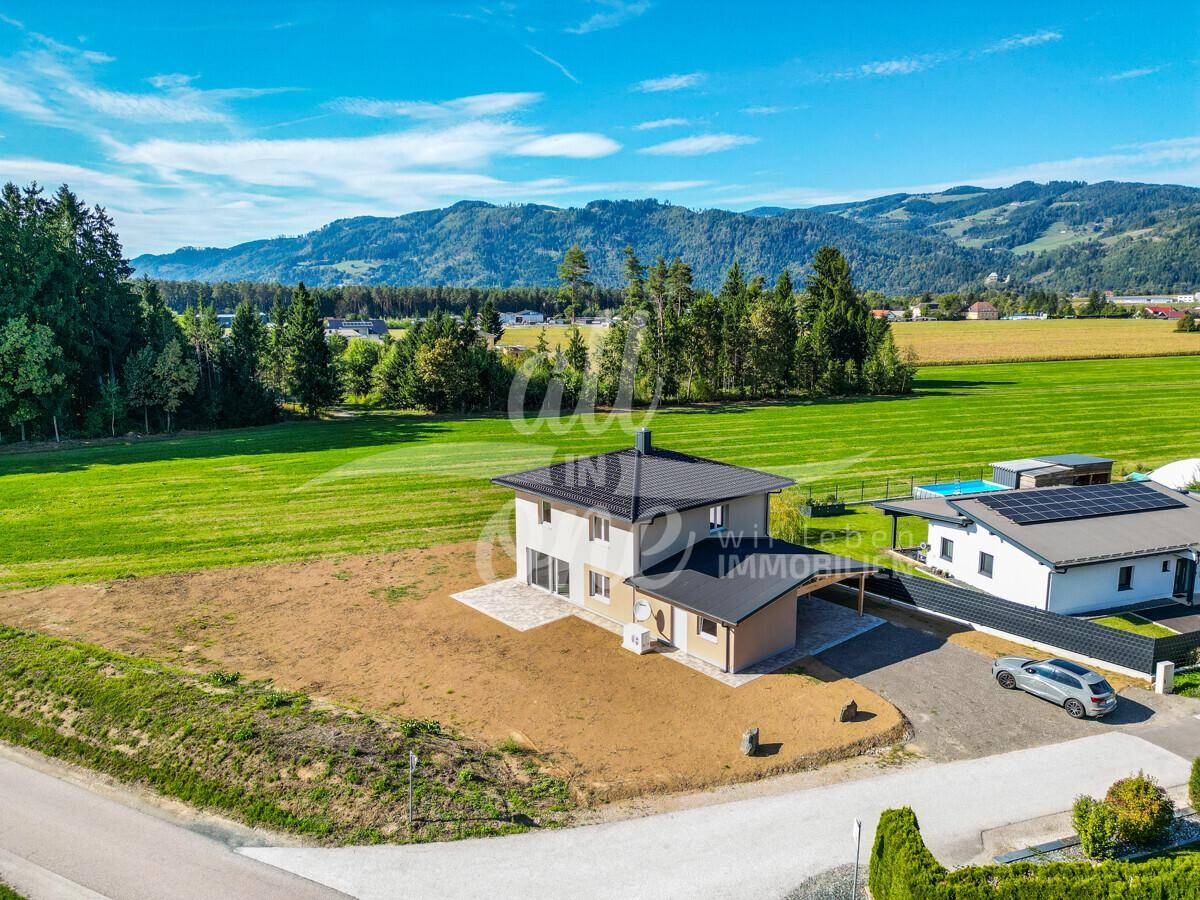 Panoramablick auf das Haus mit Nachbargebäuden und beeindruckender Bergkulisse im Hintergrund.