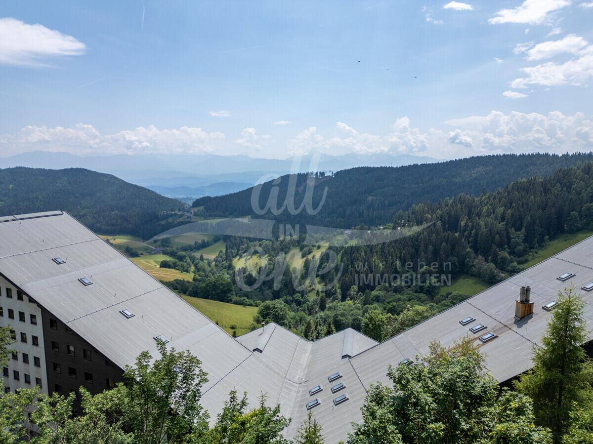 Panoramablick auf die weite Berglandschaft und grüne Täler von einem erhöhten Standpunkt.