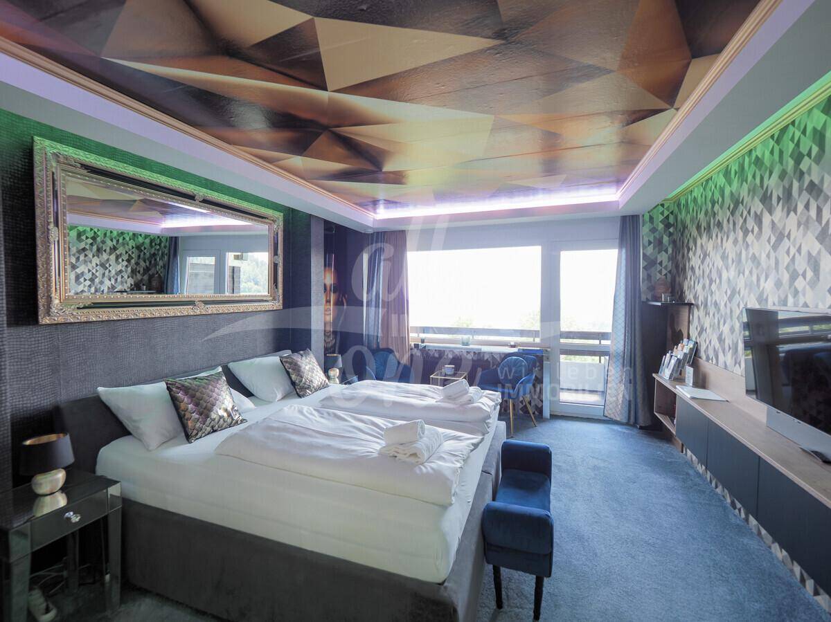 Modernes Schlafzimmer mit zwei Betten, großem Fenster und auffälliger geometrischer Decken- und Wandgestaltung.