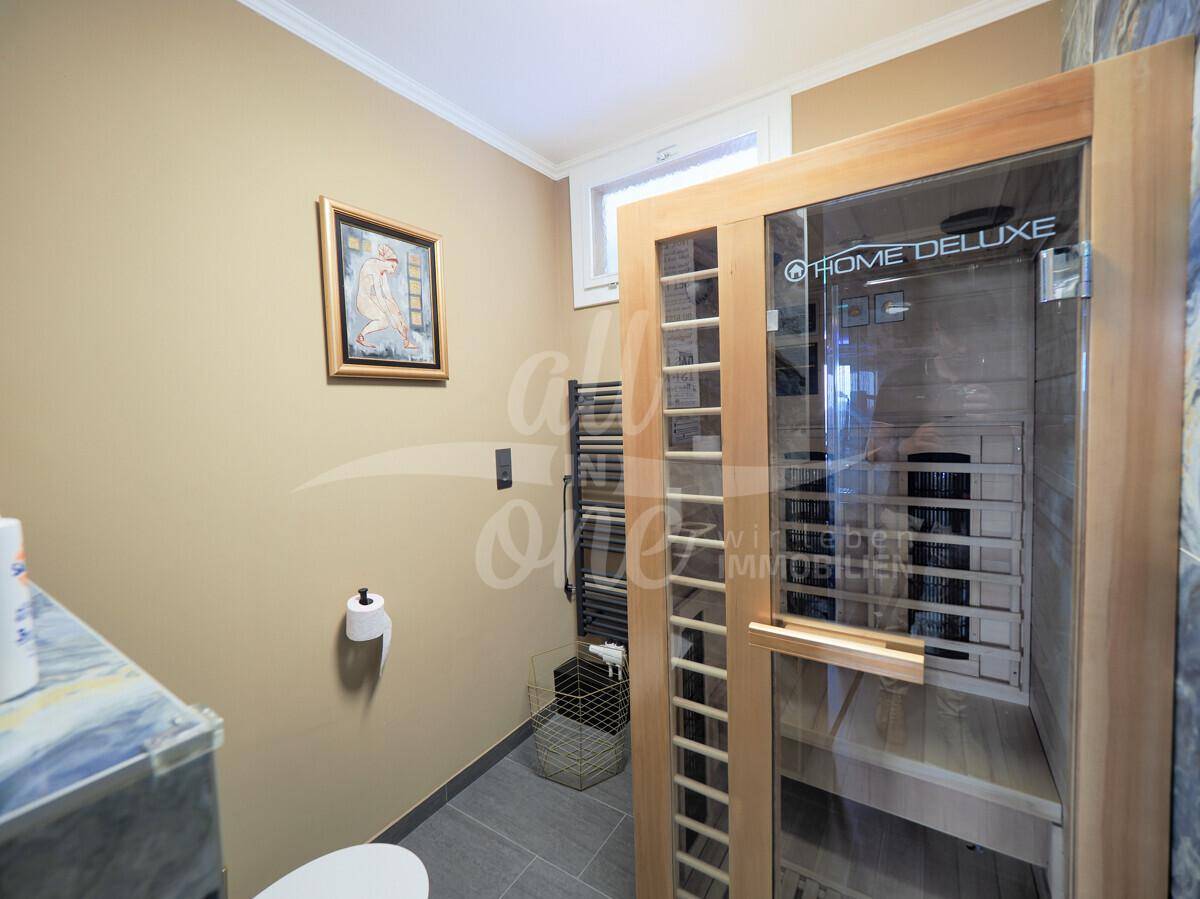 Kleines Badezimmer mit einer modernen Sauna, beheiztem Handtuchhalter und schlichten Fliesen.