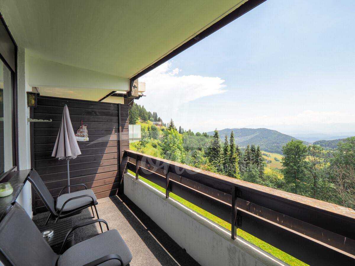 Gemütlicher Balkon mit Sitzgelegenheiten und einem weiten Blick auf die umliegende Berglandschaft.