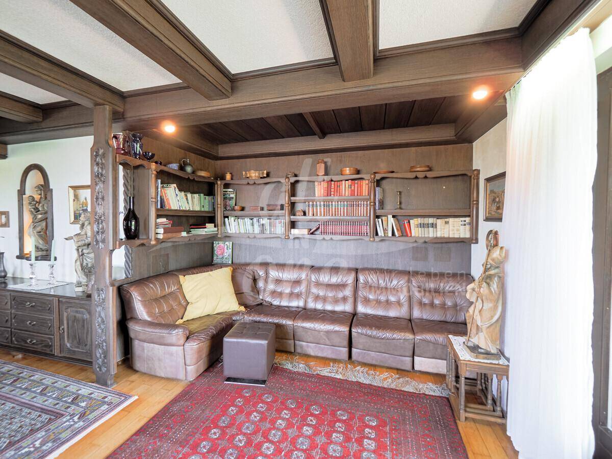 Geräumiges Wohnzimmer mit Ledersofa, Holzbalkendecke und integrierten Bücherregalen.