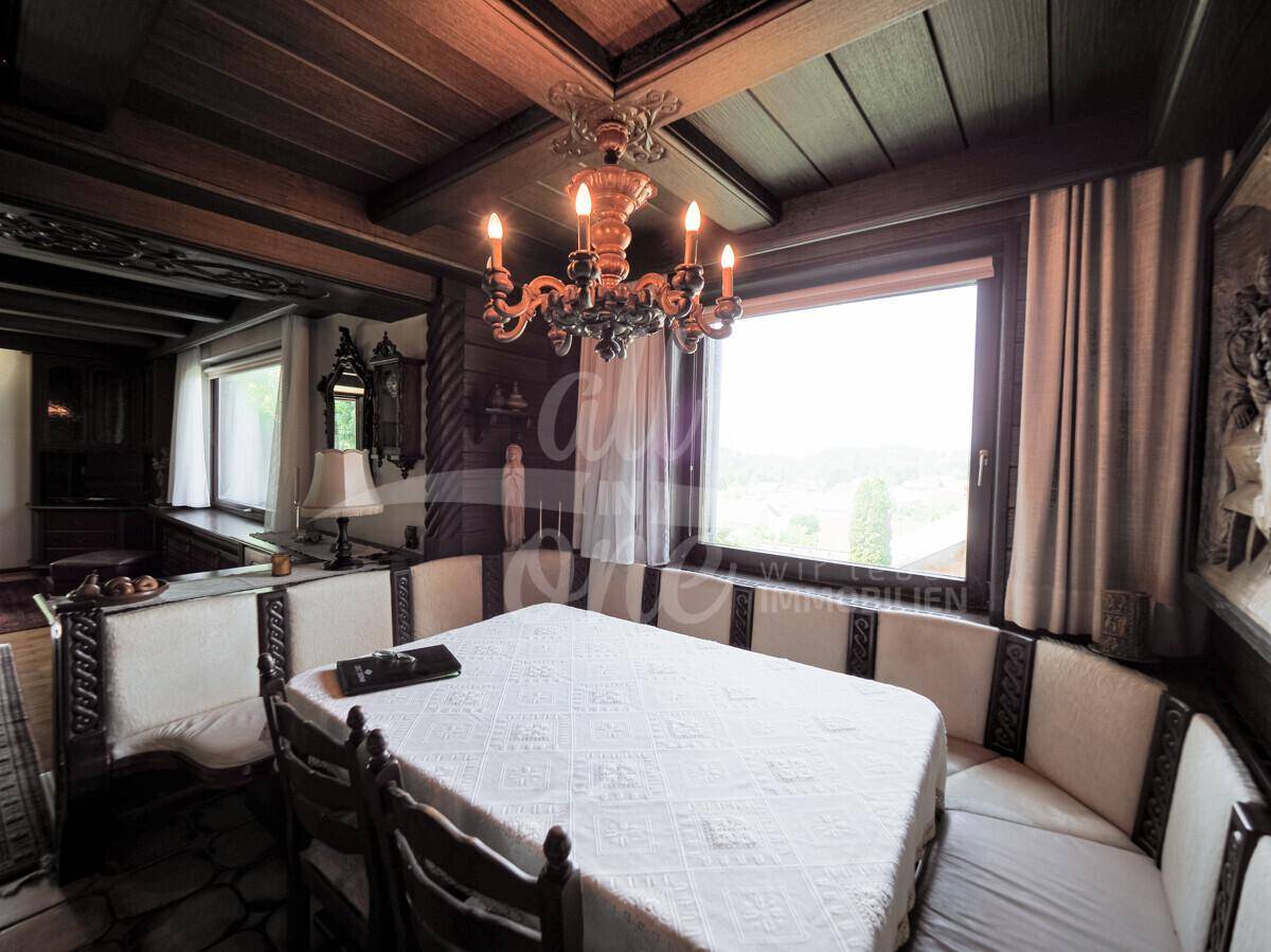 Traditioneller Essbereich mit Holzbalkendecke, Eckbank und großem Fenster mit Ausblick.
