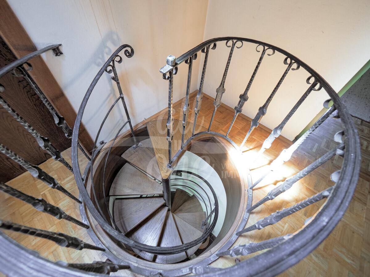 Elegante Wendeltreppe mit schmiedeeisernem Geländer und Holzstufen verbindet die Etagen.