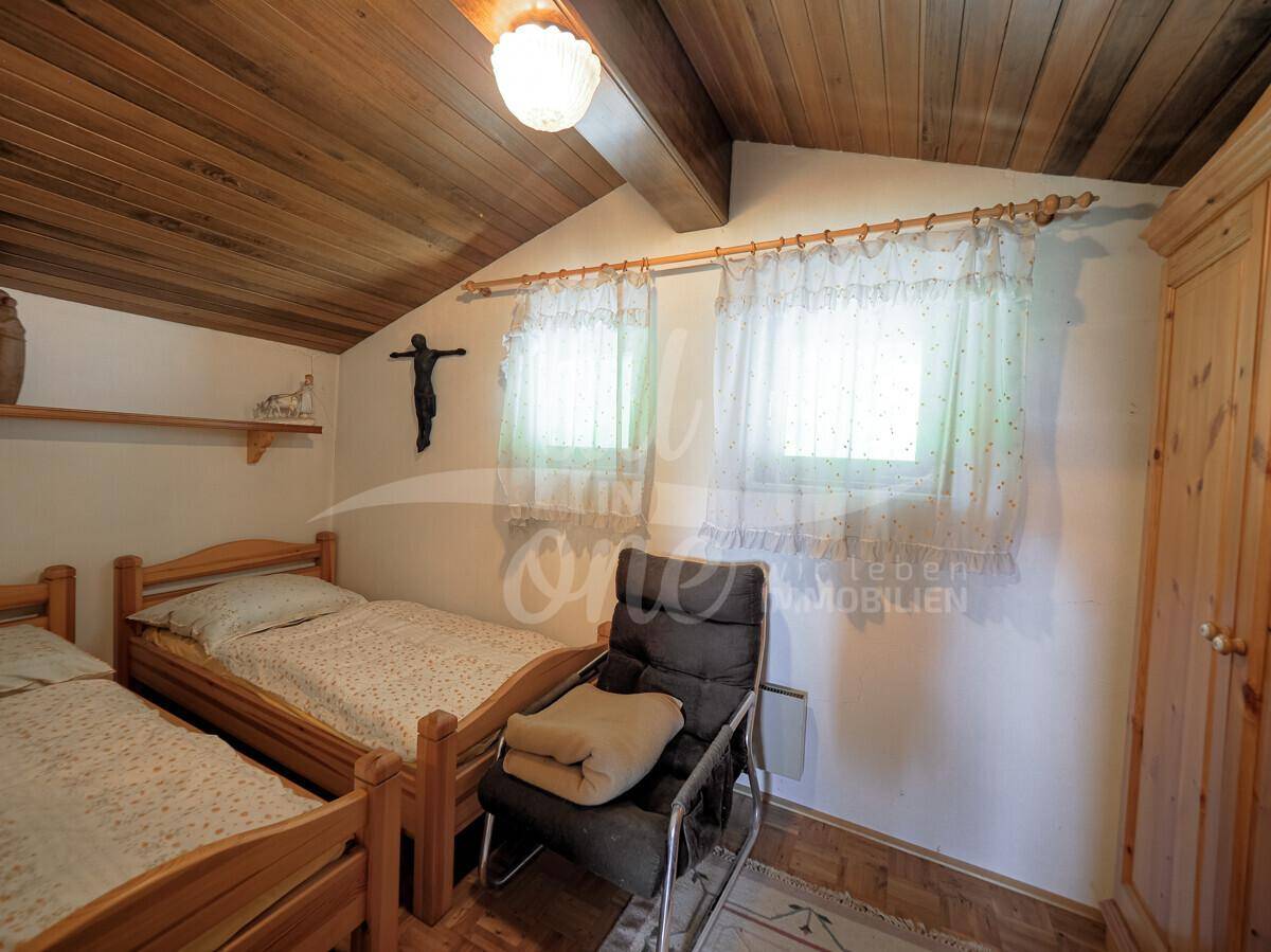 Gemütliches Schlafzimmer mit zwei Einzelbetten, Holzdecke und traditioneller Dekoration.