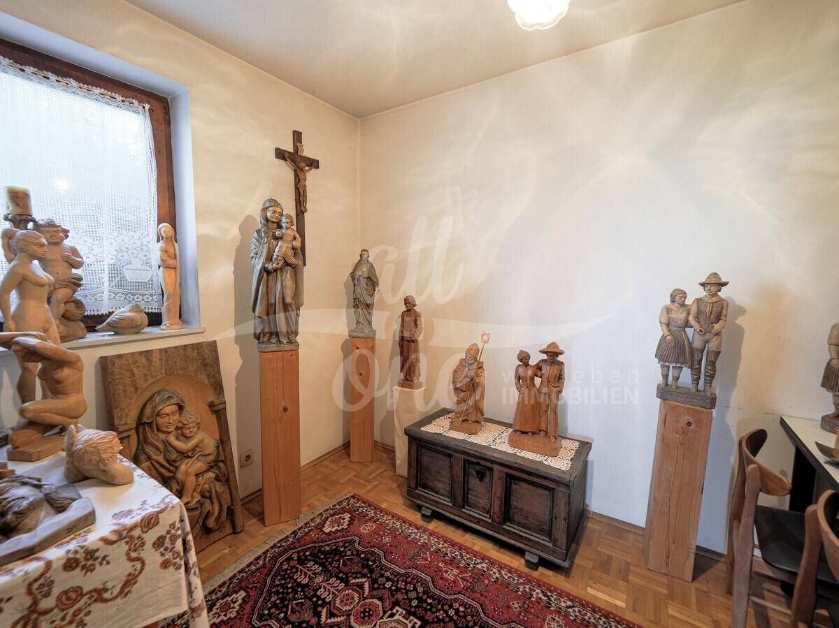 Raum mit Holzboden und verschiedenen Holzskulpturen, möglicherweise ein Hobby- oder Abstellraum.