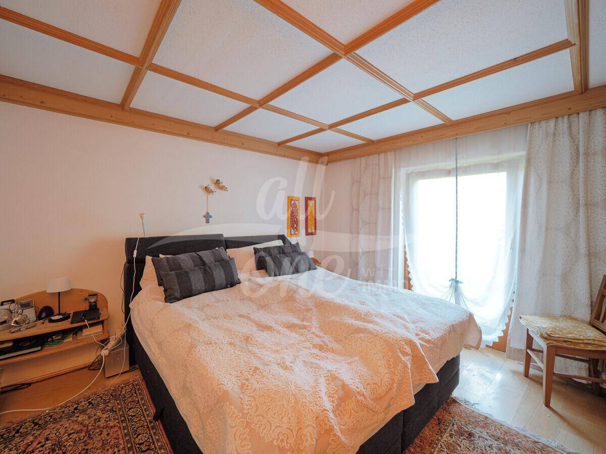 Schlafzimmer mit Kassettendecke aus Holz, großem Fenster und einem bequemen Doppelbett.