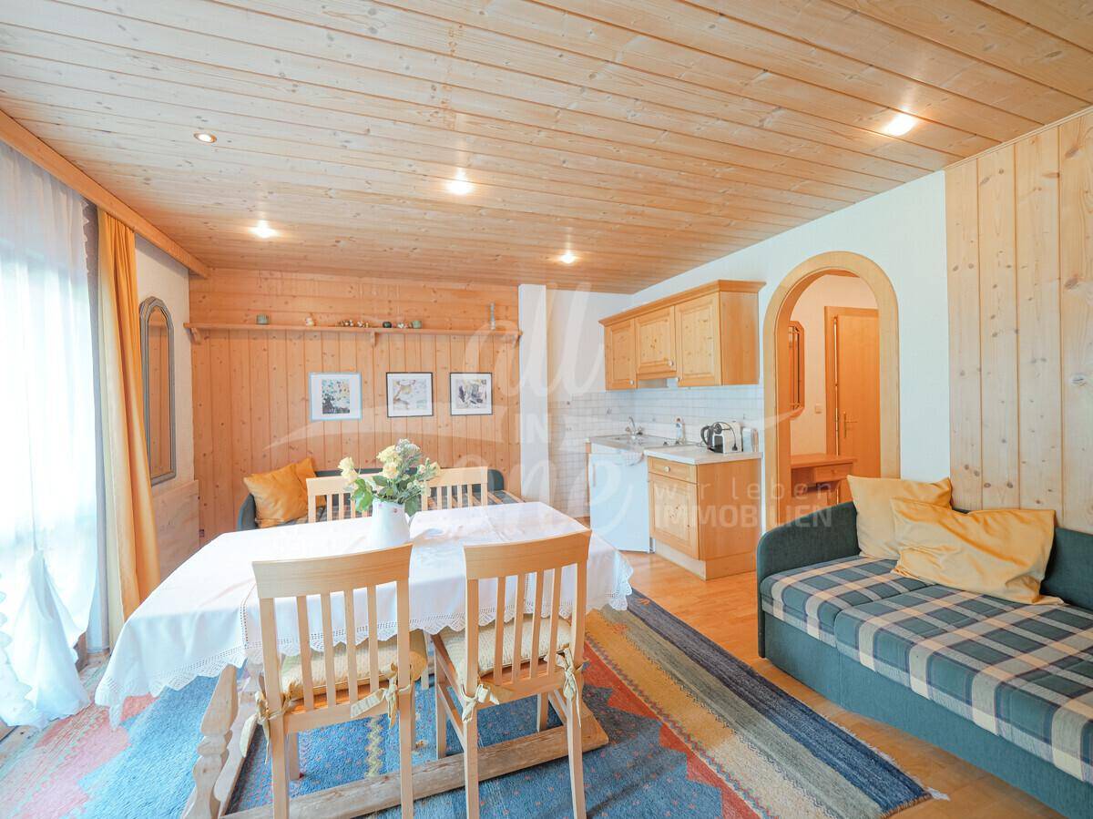 Gemütlicher Wohn- und Essbereich mit Holztäfelung, integrierter Küchenzeile und traditioneller Einrichtung.