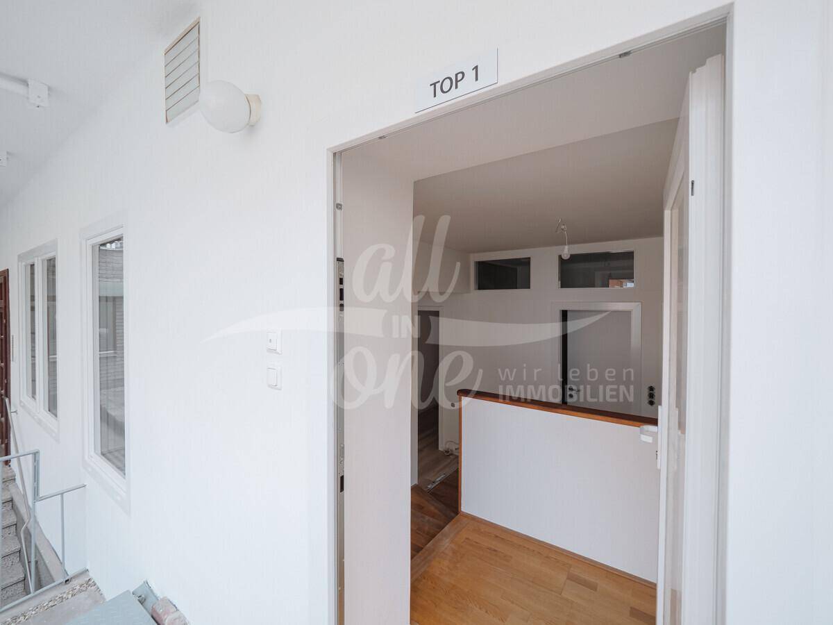 Eingangsbereich einer Wohnung mit hellem Holzboden und Blick in den offenen Wohnbereich.