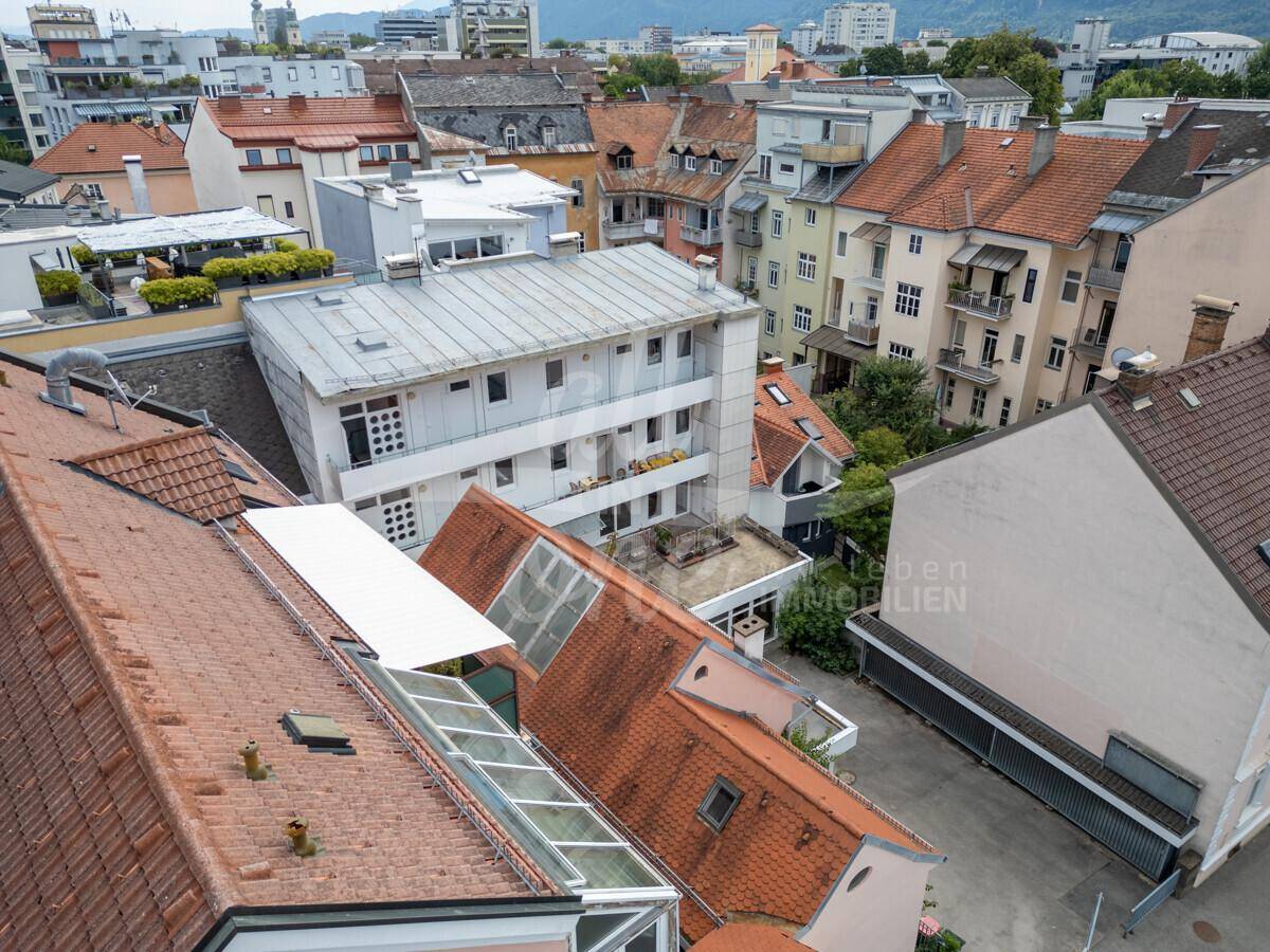 Weitläufige Dachlandschaft mit Blick auf die umliegenden Gebäude und eine begrünte Terrasse.