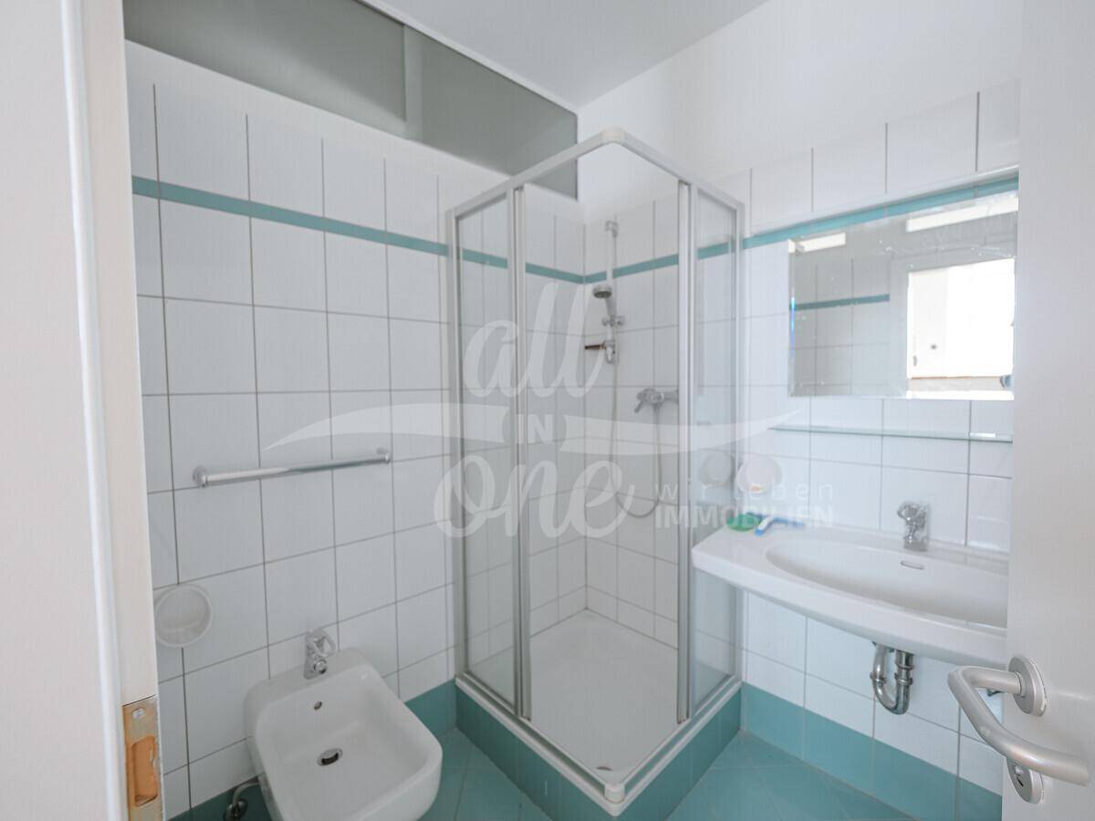 Funktionales Badezimmer mit Duschkabine, Bidet und hellblauen Fliesen, gut erhalten.