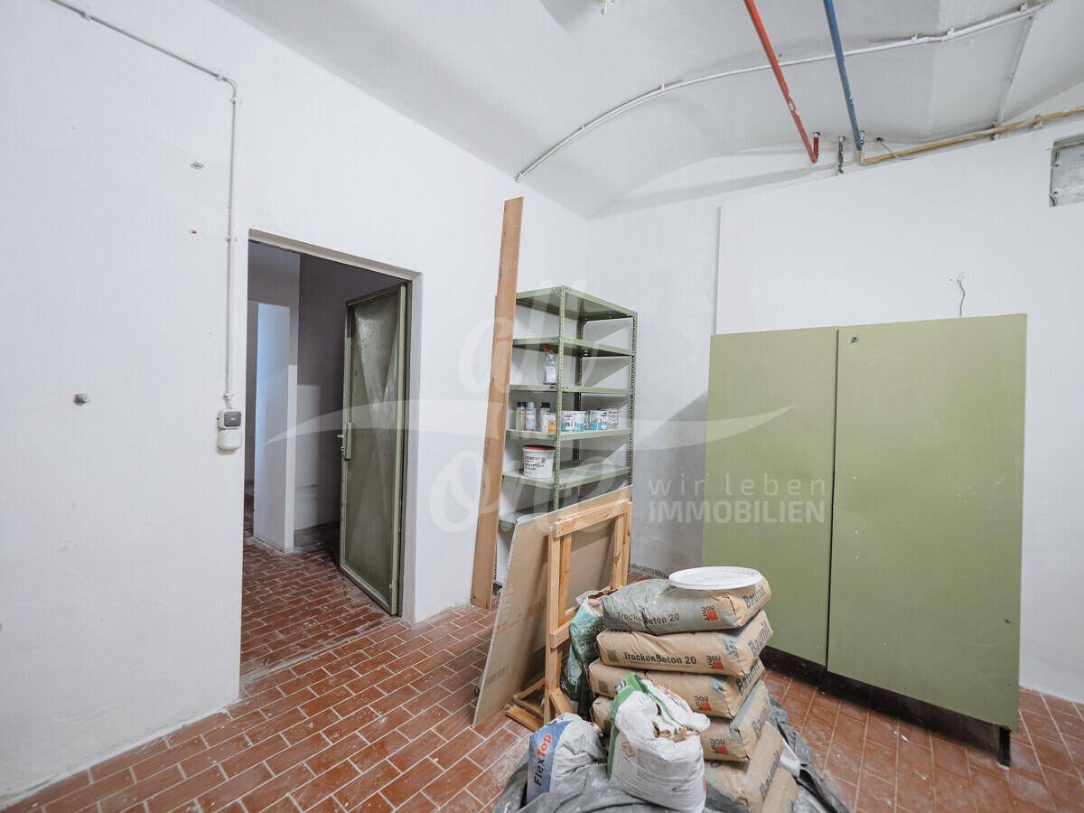 Kellerraum mit Ziegelboden und Regalen, bietet viel Stauraum für diverse Gegenstände.