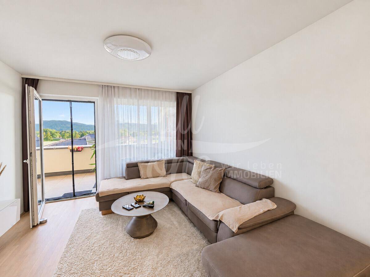 Helles Wohnzimmer mit großem Ecksofa und direktem Zugang zum Balkon mit Bergblick.
