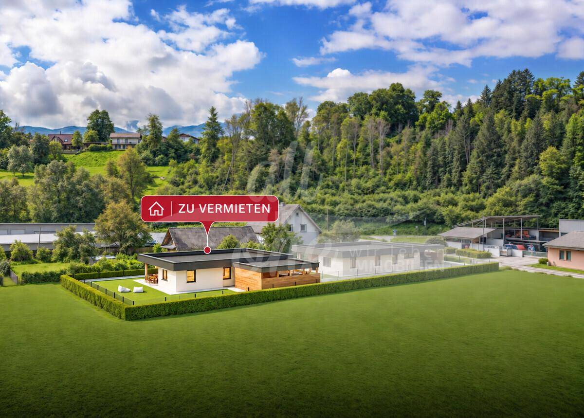 Luftaufnahme eines modernen Hauses in ländlicher Umgebung mit viel Grün und Bergen im Hintergrund.