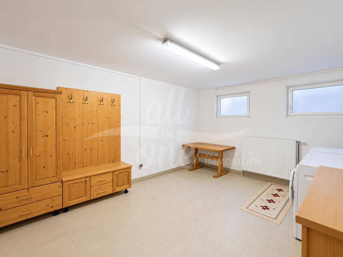 Geräumiger und heller Kellerraum mit Fliesenboden und Holzmöbeln, vielseitig nutzbar.