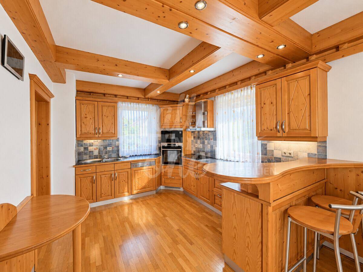 Rustikale Holzküche mit Einbaugeräten, Essbereich und sichtbaren Deckenbalken.