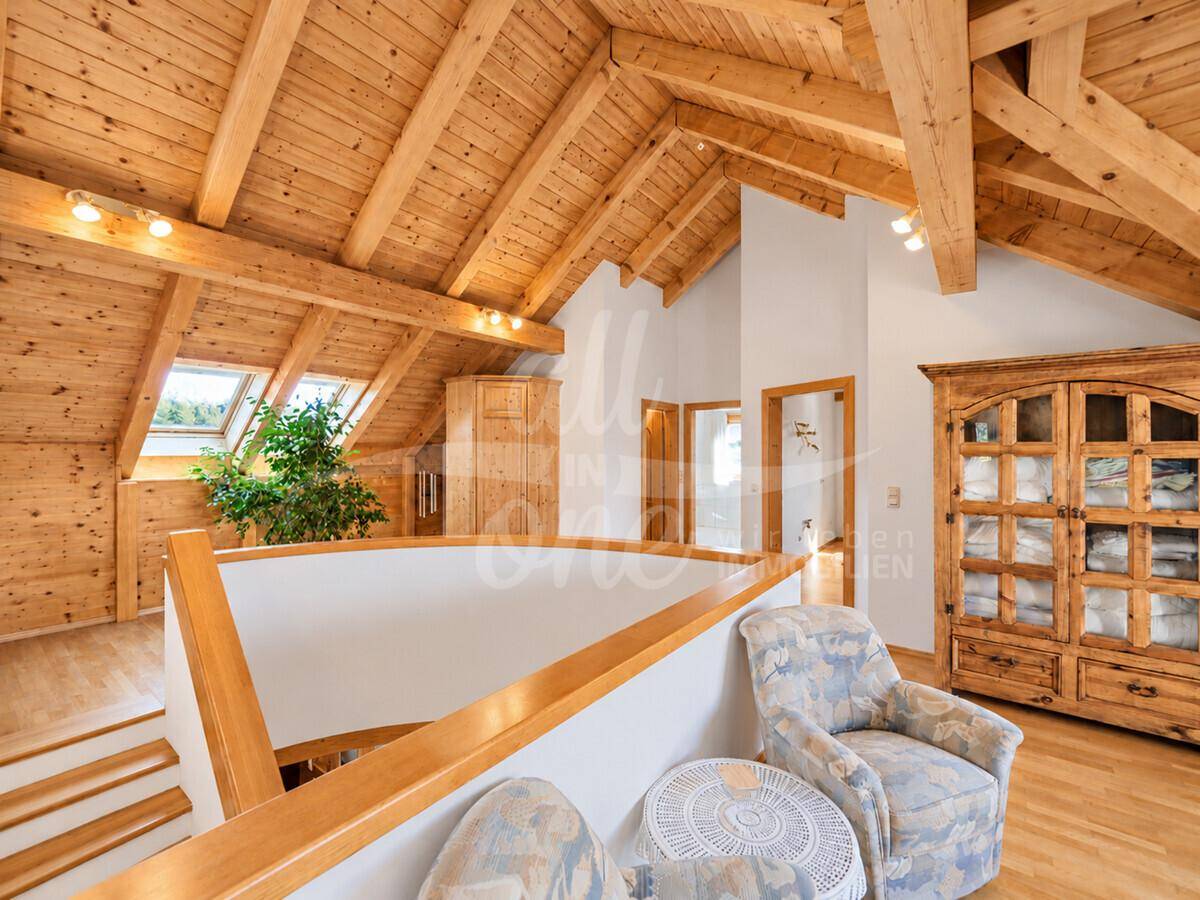 Heller Flurbereich im Obergeschoss mit Holzbalkendecke und großem Holzschrank.
