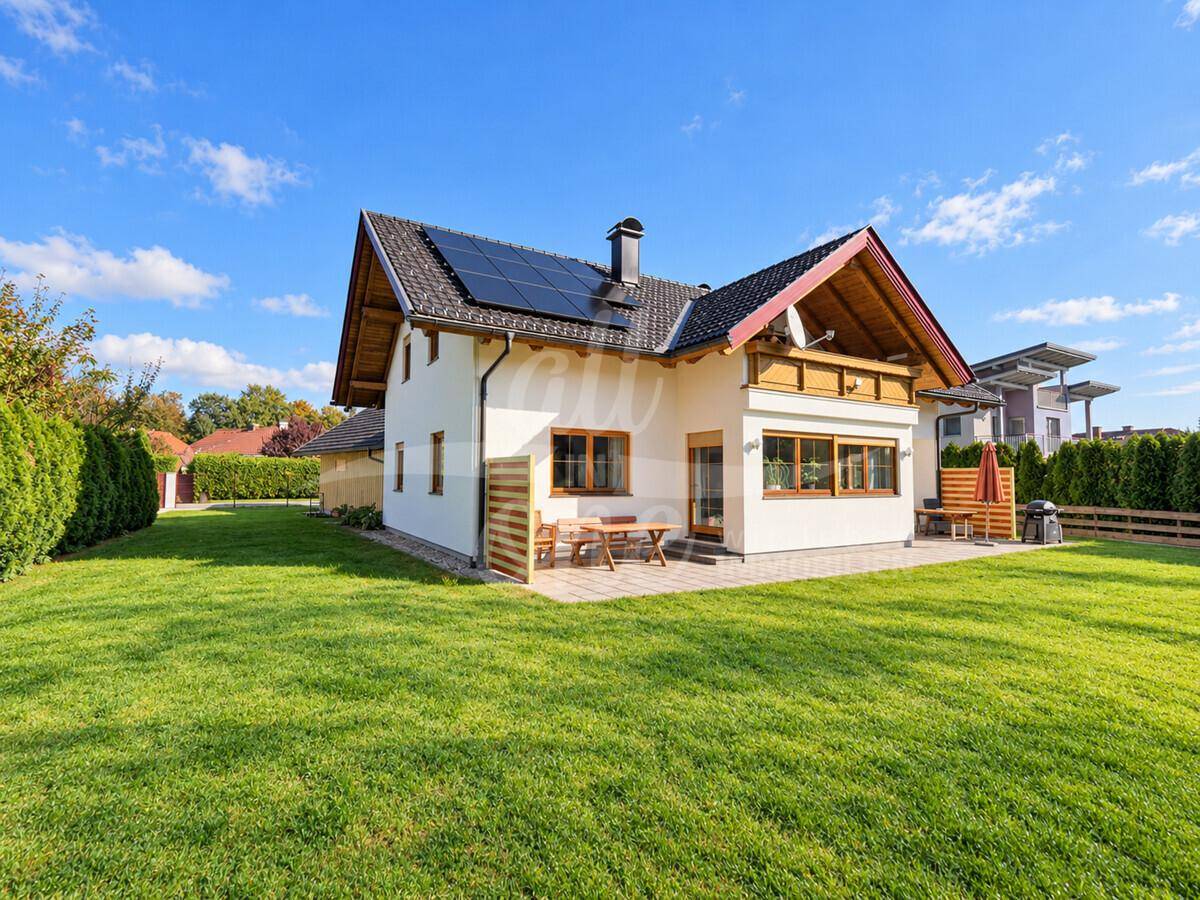 Rückansicht des Hauses mit großer Rasenfläche, Terrasse und Solaranlage auf dem Dach.