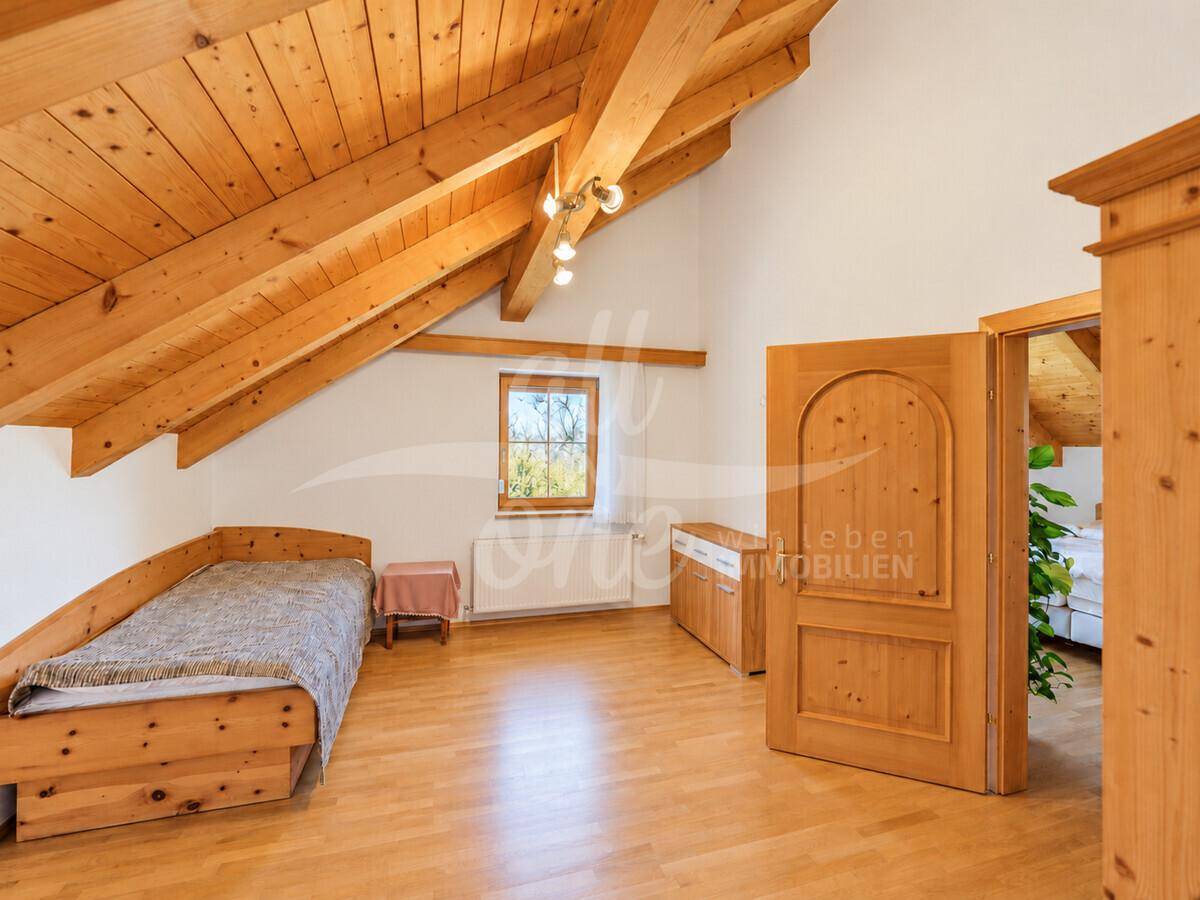 Gemütliches Schlafzimmer im Dachgeschoss mit Holzbalkendecke und Holzboden.