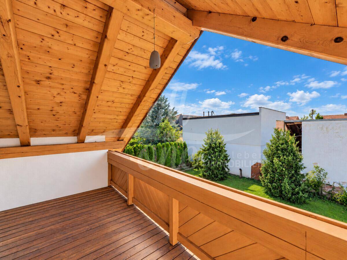 Geräumiger Holzbalkon mit Blick ins Grüne, ideal zum Entspannen im Freien.