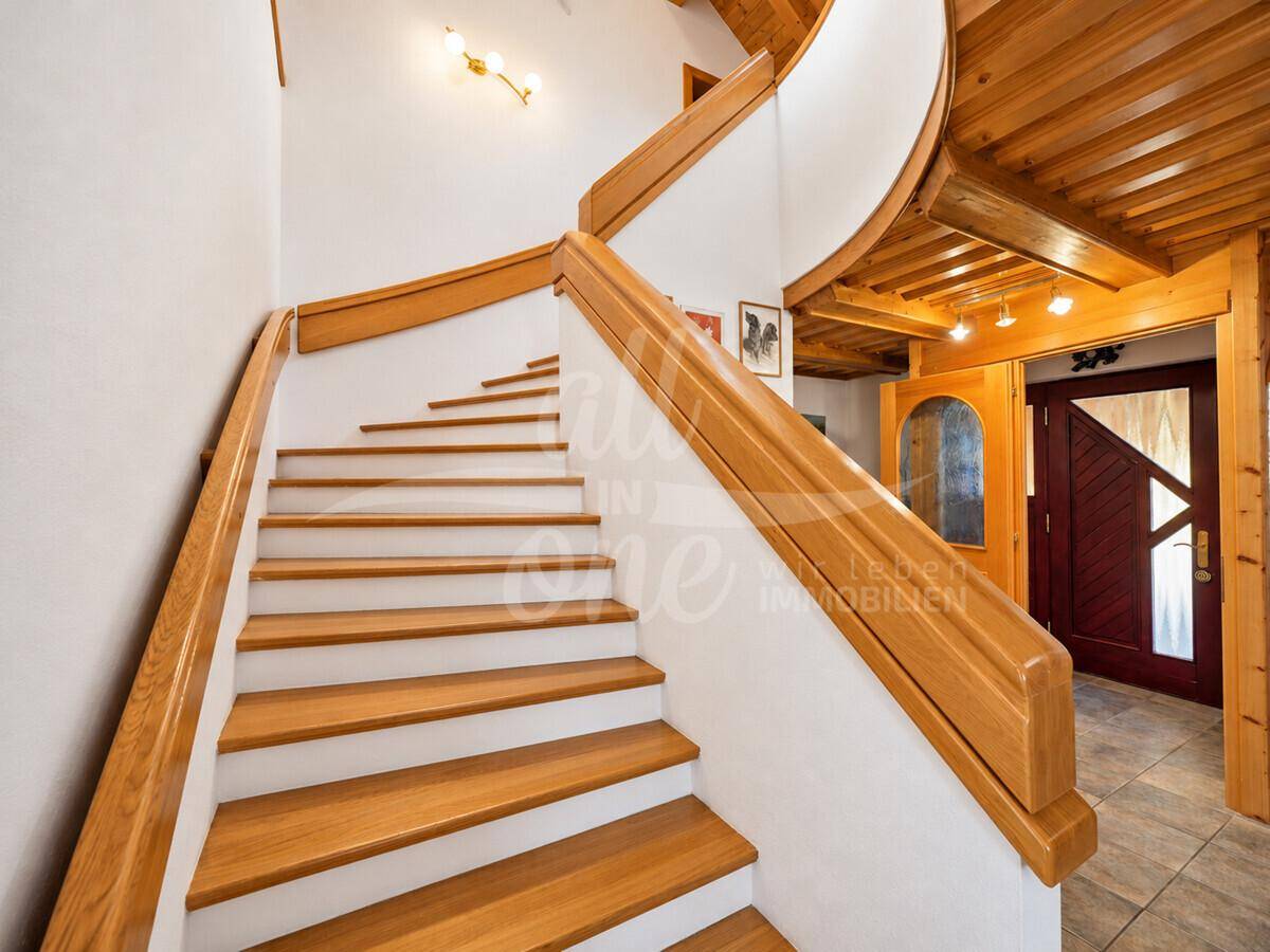 Elegante Holztreppe mit weißem Geländer, die die verschiedenen Ebenen des Hauses verbindet.