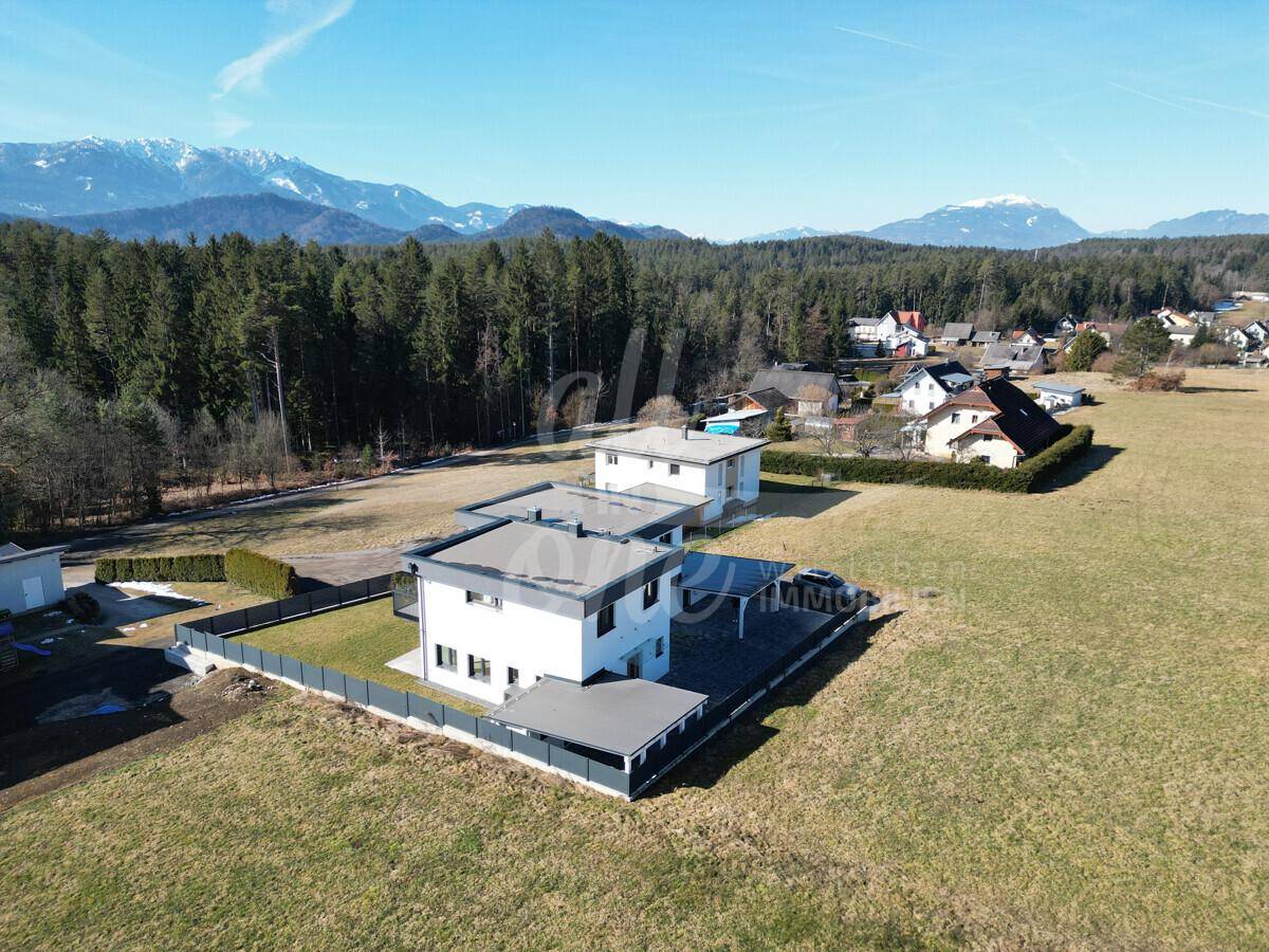 Luftaufnahme von mehreren modernen Häusern in einer ländlichen Umgebung mit Bergblick.