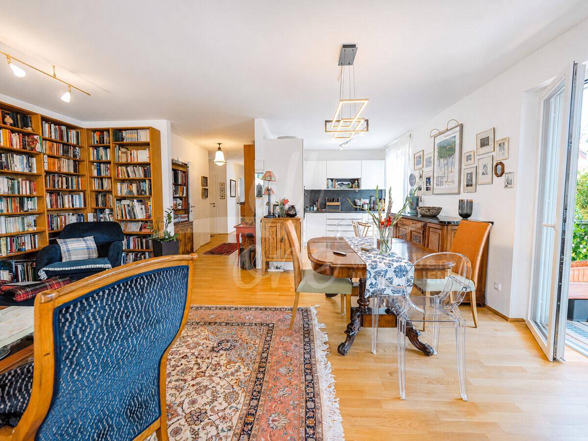 Offener Wohn-Essbereich mit integrierter Küche, Parkettboden und einer großen Bücherwand.