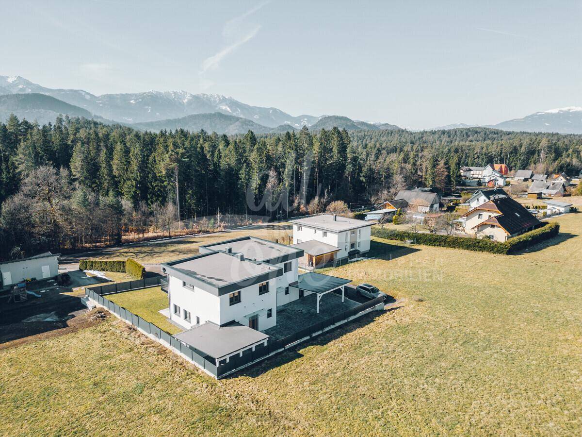 Weitläufige Luftaufnahme von Neubauten mit Bergblick und umgebenden Feldern.