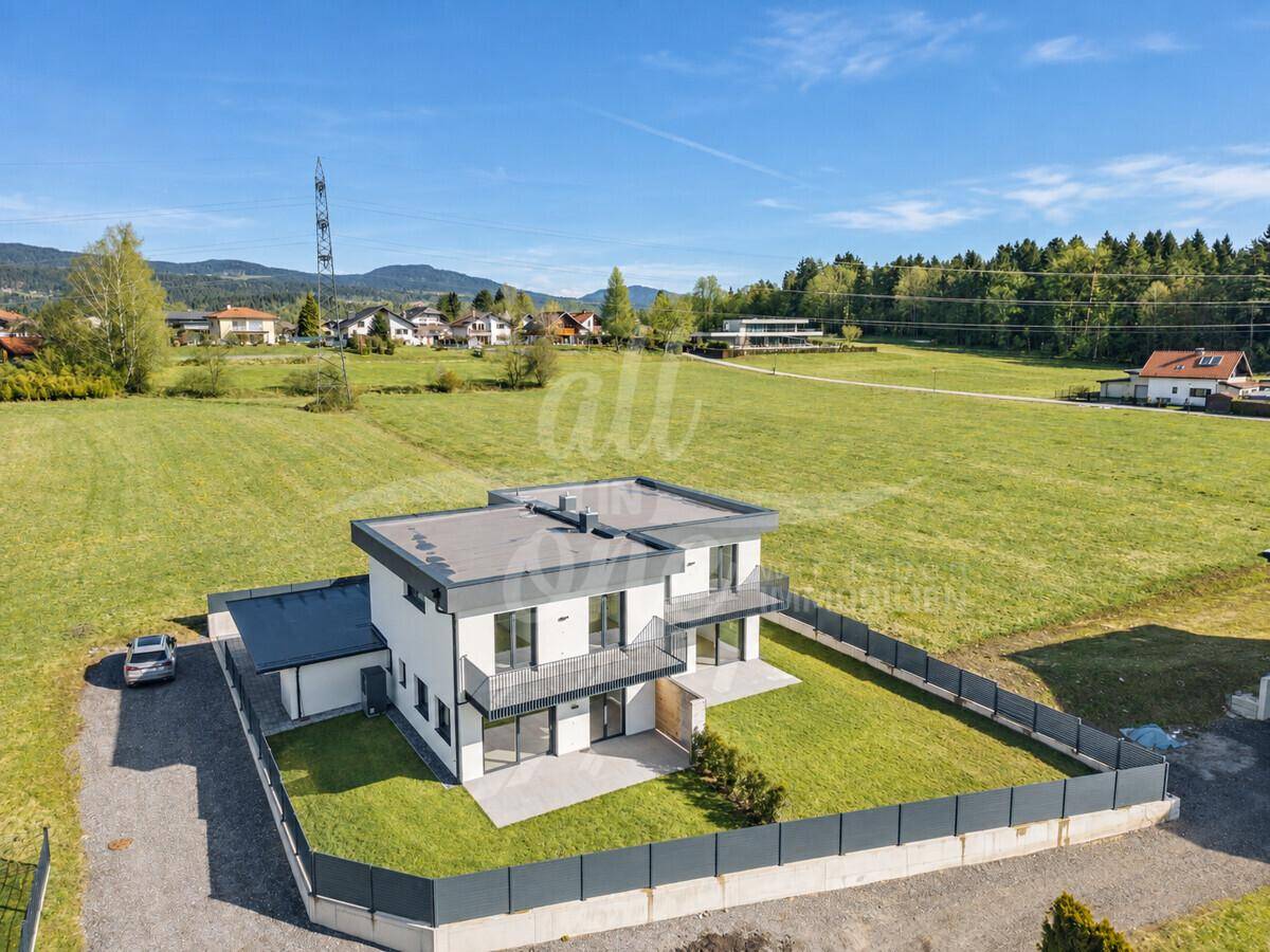 Luftaufnahme des modernen Hauses mit Garten, Terrasse und umliegender Landschaft.