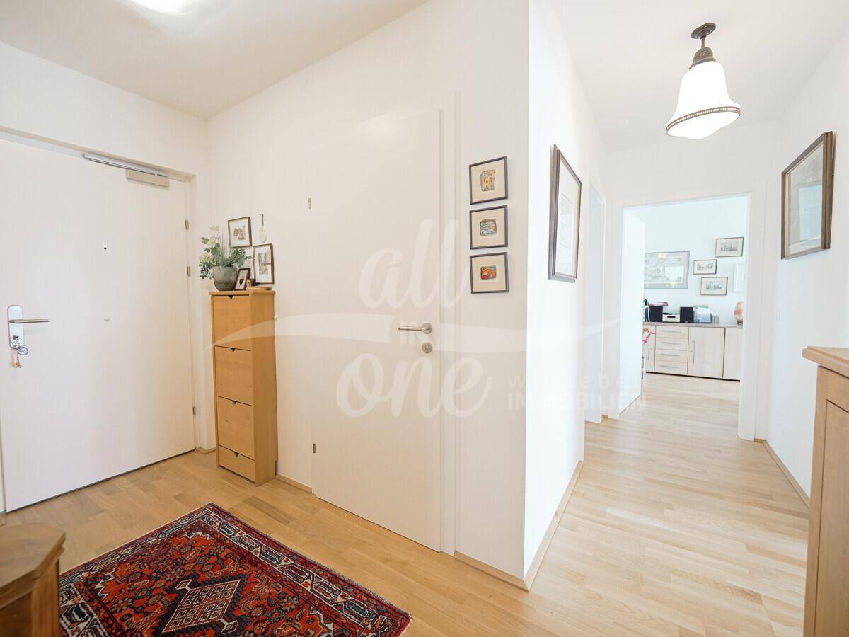 Heller Eingangsbereich mit Parkettboden, Schuhschrank und dekorativen Bildern an den Wänden.