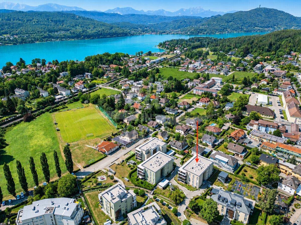 Übersicht der Wohnanlage aus der Vogelperspektive mit See- und Bergblick, die Lage des Objekts markierend.