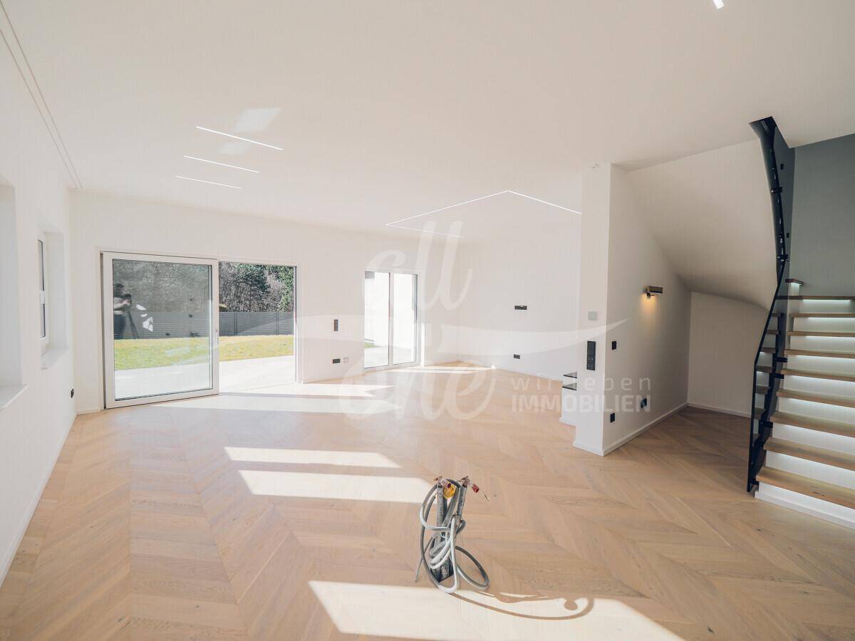 Geräumiger Wohnbereich mit Parkettboden, moderner Treppe und viel Tageslicht.