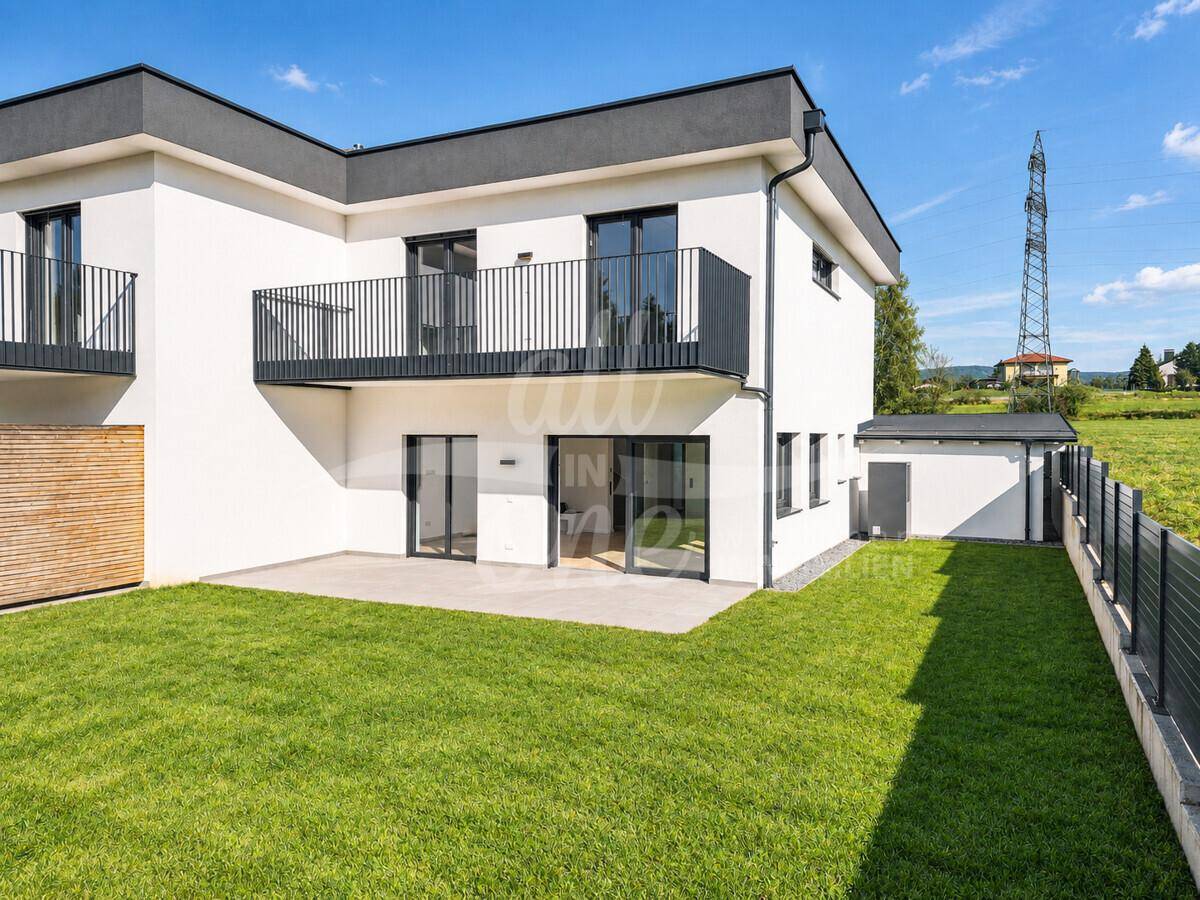 Rückansicht des modernen Hauses mit großer Terrasse und Zugang zum Garten.