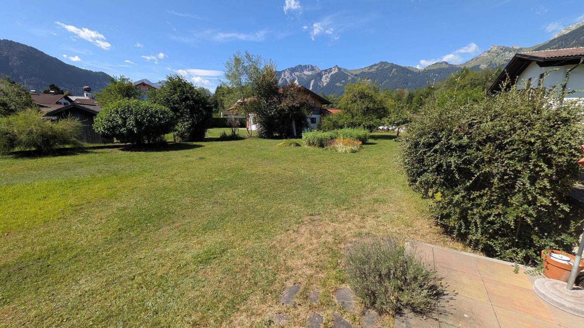 Weitläufiger Gartenbereich mit Terrasse und beeindruckendem Panoramablick auf die Berge.