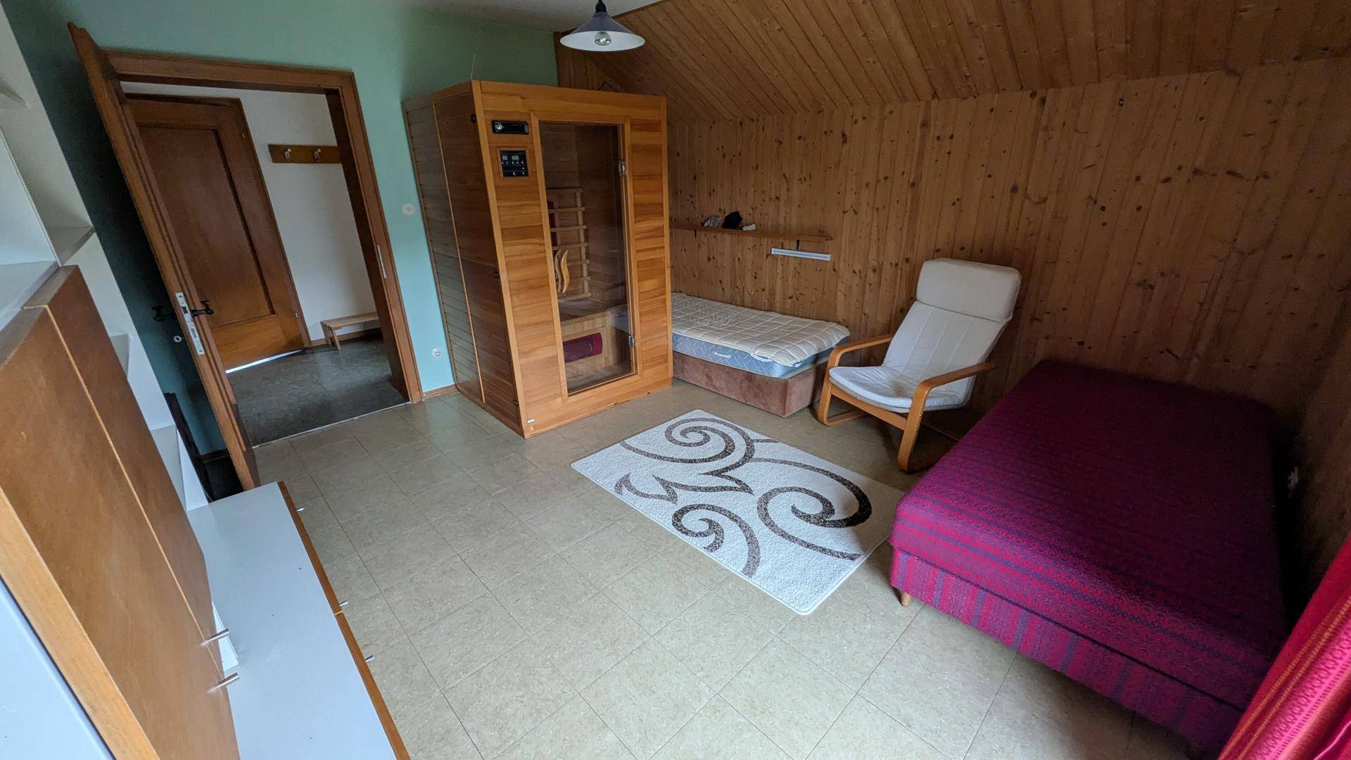 Raum mit privater Sauna, Holzvertäfelung und zusätzlichem Schlafplatz unter Dachschräge.