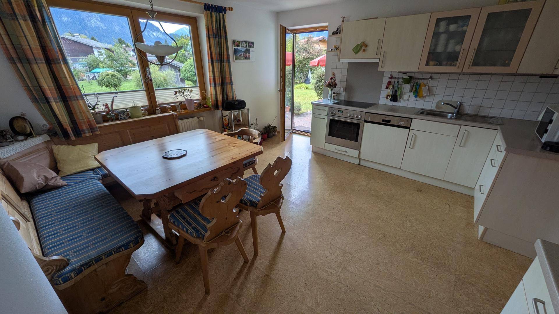 Wohnküche mit traditioneller Essecke, weißen Schränken und Blick in den Garten.