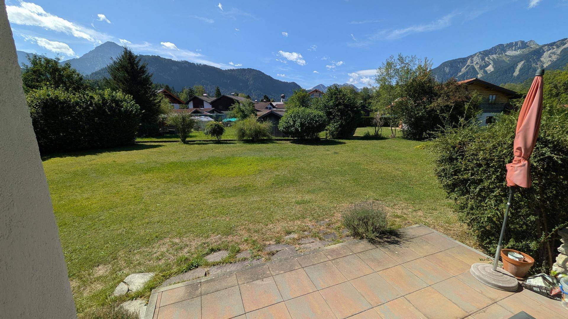 Große Terrasse mit Blick auf den weitläufigen Garten und die umliegende Berglandschaft.