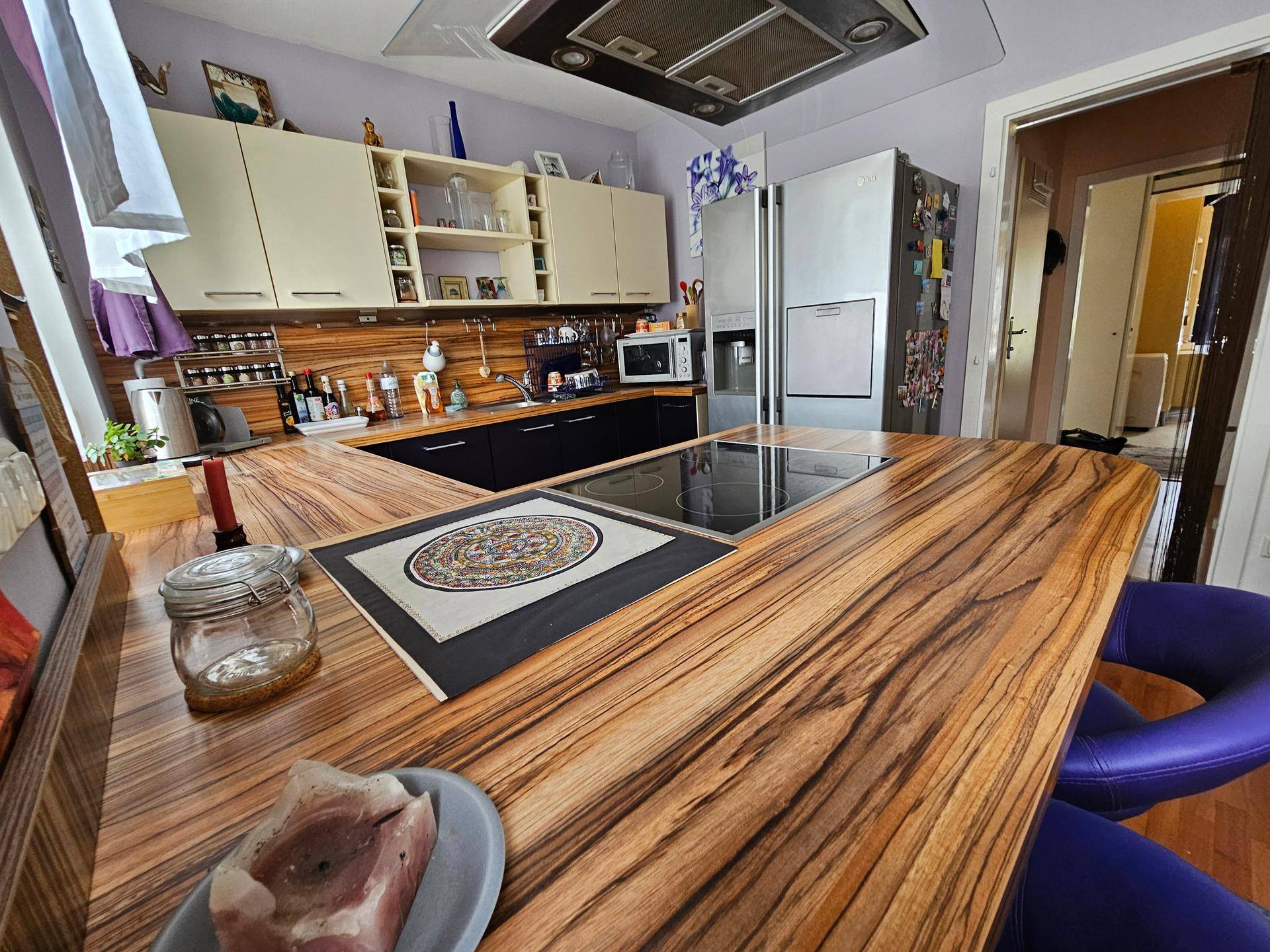 Detailansicht der Kücheninsel mit Induktionskochfeld und gemaserten Holz-Arbeitsplatten.