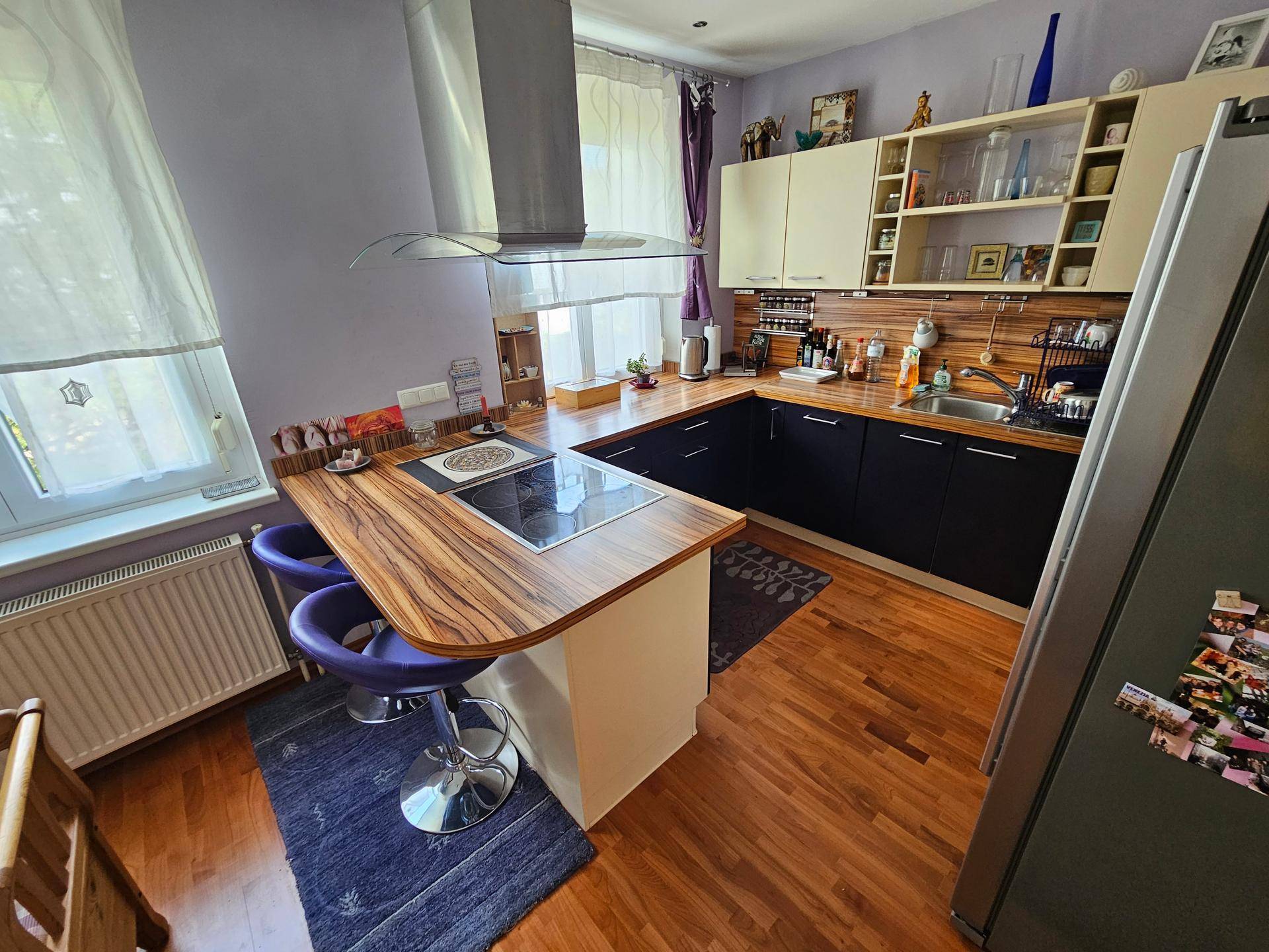 Funktionale Küche mit schwarzen und weißen Schränken, Holz-Arbeitsplatten und Frühstücksbar.