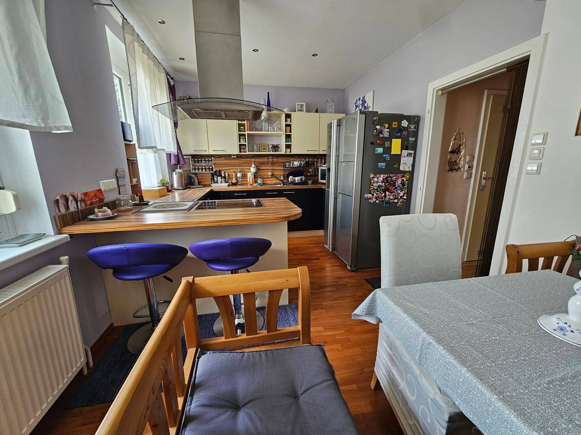 Geräumige Küche mit Essbereich, Kühlschrank und Zugang zu einem weiteren Raum.