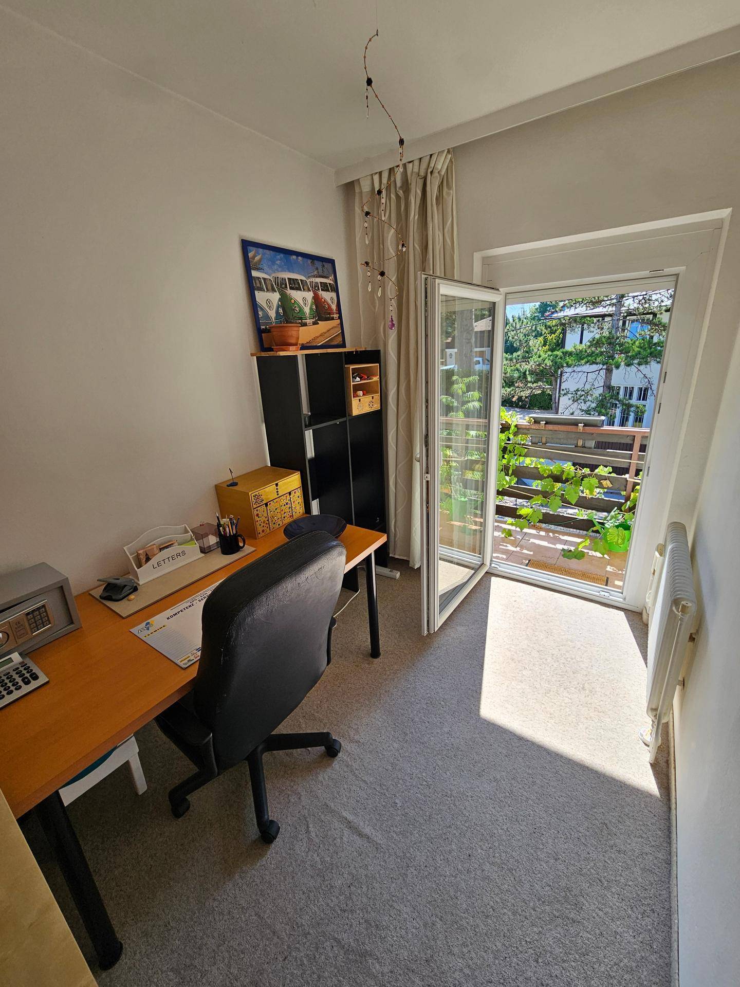Arbeitszimmer mit Schreibtisch, Bürostuhl und direktem Zugang zu einem Balkon.