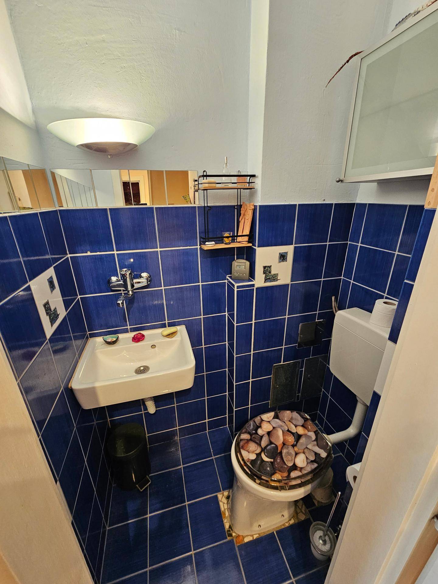 Kleines Gäste-WC mit blauen Fliesen, Waschbecken und Toilette.